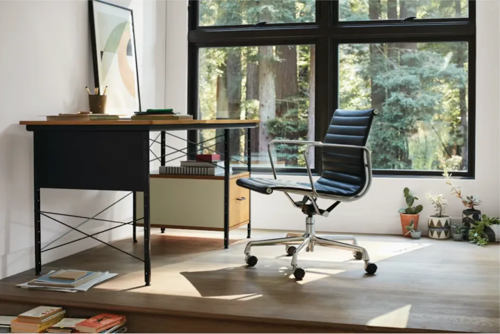 Black Eames Aluminum Group chair in modern office with window view